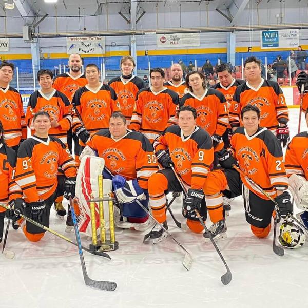 Une équipe de hockey en maillots orange pose sur la glace de l'aréna. 
