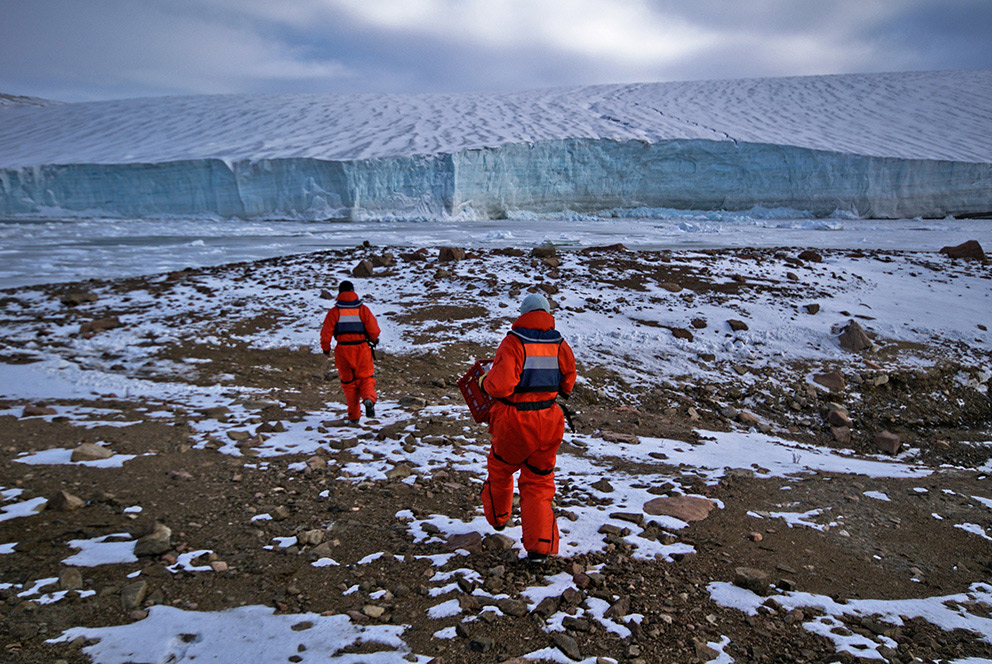 2 researchers walking towards a glacier.
