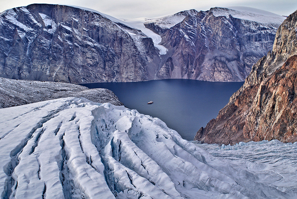 Vue du haut d'une colline sur le NGCC Amundsen se trouvant dans un fjord.