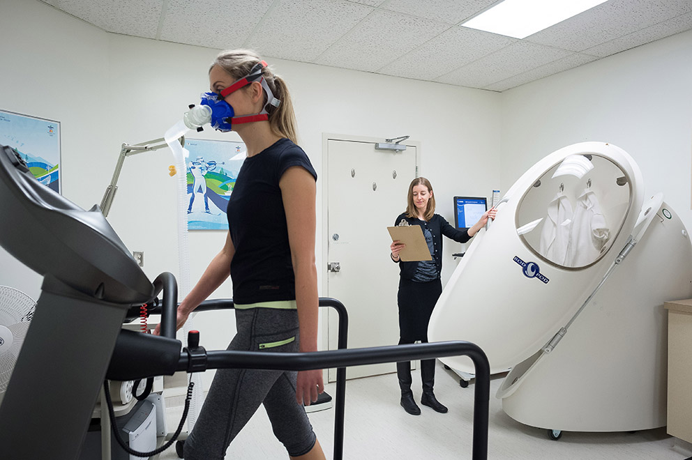 Researcher Kristin Campell operating research infrastructure while a patient walks on a treadmill.