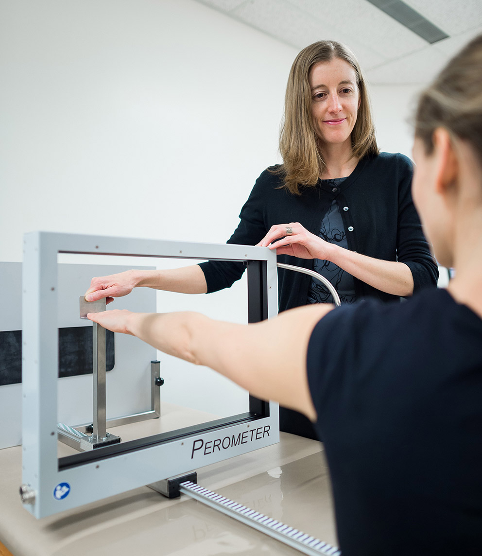 La chercheuse Kristin Campell utilise un peromètre pour mesurer le volume du bras d'une patiente.