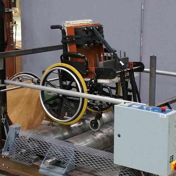 A wheelchair is strapped in testing equipment in a laboratory.