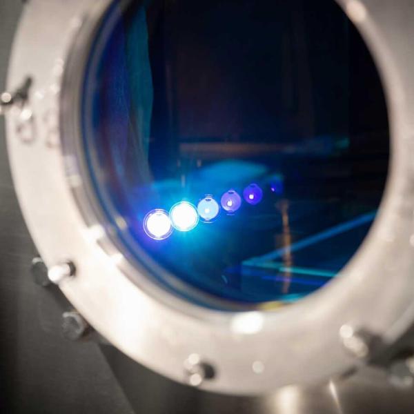 A close-up view of a vacuum chamber with several points of light in focus inside a circular window.